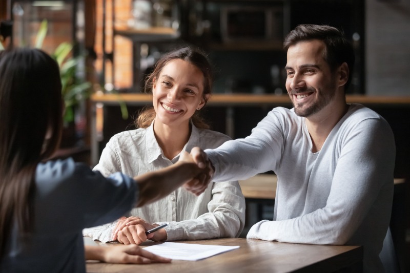 Happy couple handshake relator thanking for help 